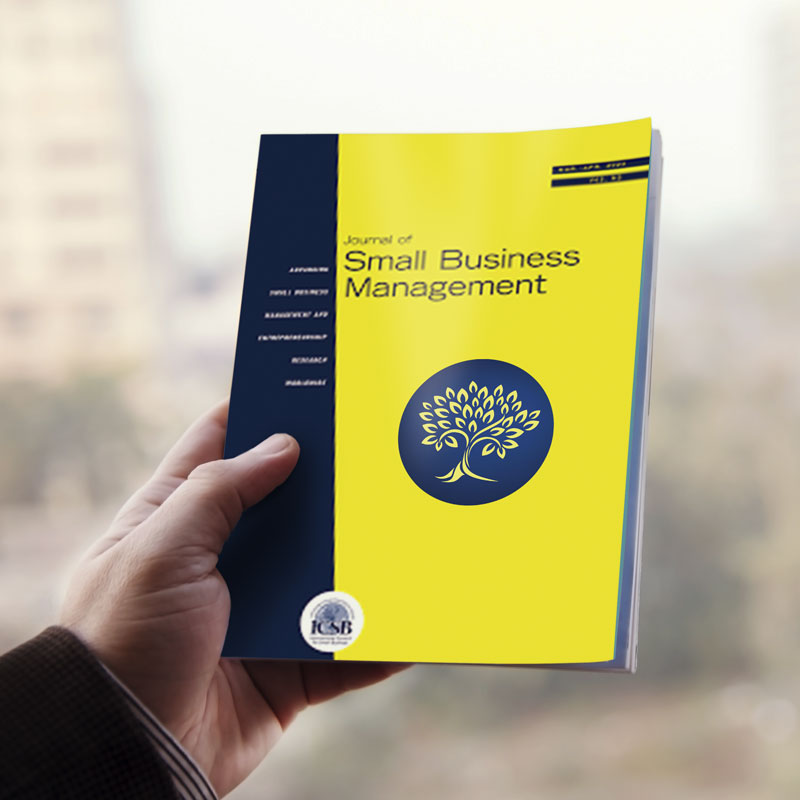 a man's hand holding a journal of small business management magazine